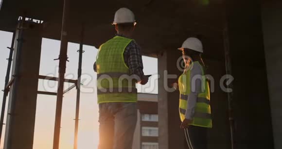 戴着防护头盔和背心的英俊建筑工人在工作时握手视频的预览图