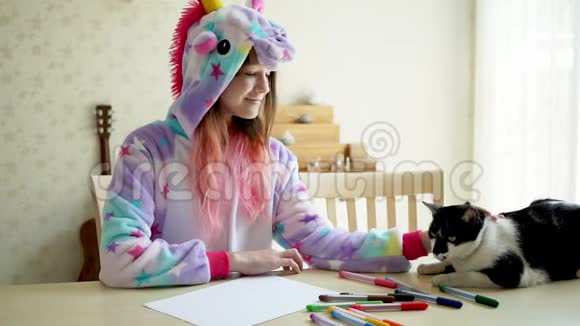 可爱的少女穿着kawaii独角兽睡衣在客厅里玩她的猫视频的预览图