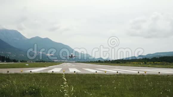 飞机从黑山蒂瓦特机场跑道起飞多云的天空群山视频的预览图
