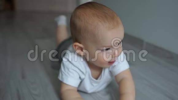 近距离拍摄一个两岁的婴儿趴在地板上拉着一支钢笔看着相机快乐视频的预览图