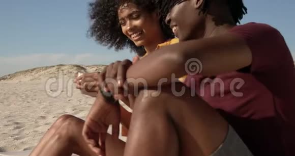 在海滩上玩贝壳的非裔美国人夫妇的侧面景色视频的预览图