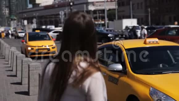 迷人的女人欣赏城市黄色的出租车经过视频的预览图