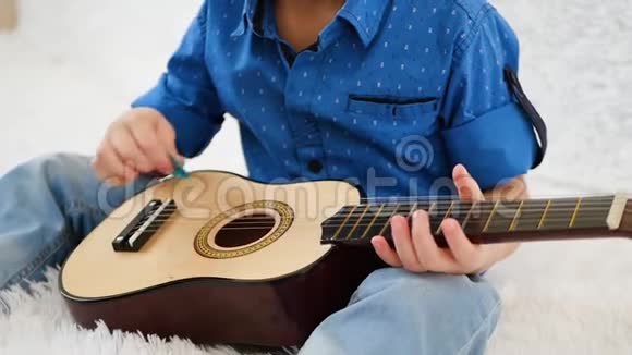 一个男孩在慢动作演奏儿童的吉他特写视频的预览图