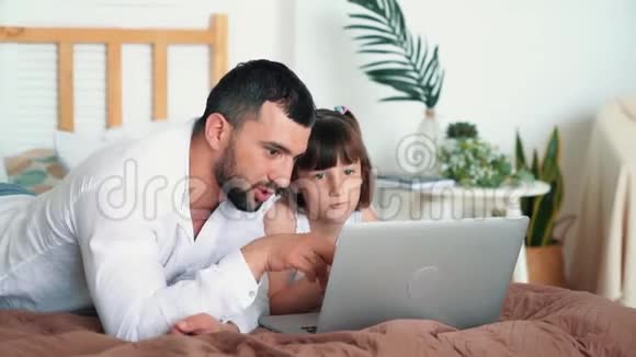 年轻的父亲和他的女儿一起学习笔记本电脑慢动作视频的预览图