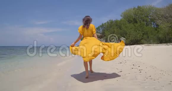 穿着黄色衣服的布鲁内特沿着海边散步漂亮的后拍拍摄海洋空气和欣赏海景视频的预览图