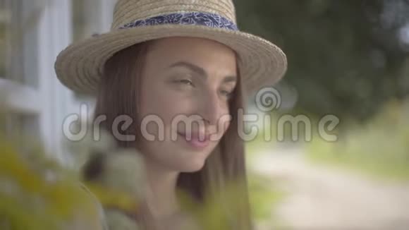 一位戴着草帽的迷人年轻女子的特写脸微笑着看着户外情感乡村生活方式自然视频的预览图