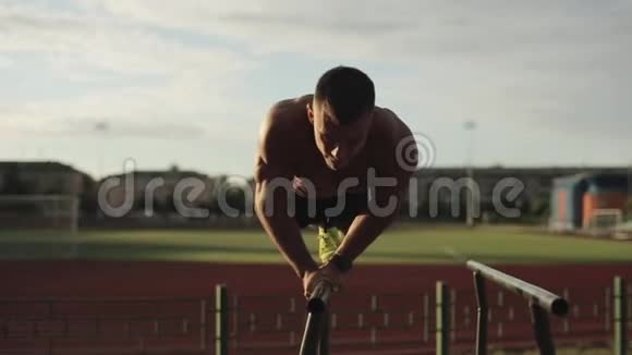 一个年轻的肌肉健美运动员用杠铃举臂的特写镜头视频的预览图