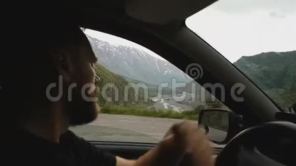 戴墨镜的胡子男开车在山路上坐车旅行视频的预览图