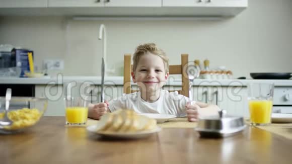 可爱的男孩坐在桌旁拿着刀叉等着另一个家庭有一个超餐镜头视频的预览图