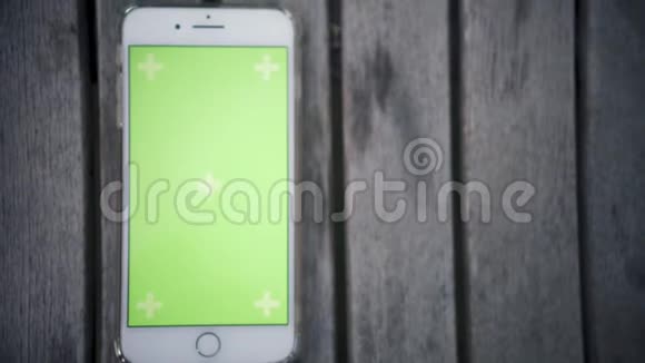 在花园里用绿色屏幕色键将电话垂直放置在木桌上视频的预览图