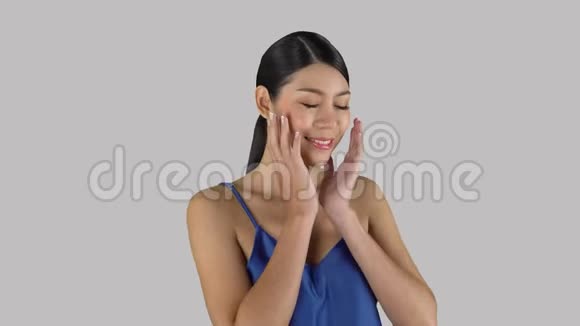 漂亮的黑发亚洲人马尾辫被隔离在浅色背景上用微笑和快乐的双手压在脸上视频的预览图