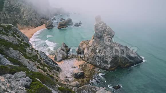 葡萄牙辛特拉普拉亚达乌尔萨海滩晨雾中的岩石4K景视频的预览图