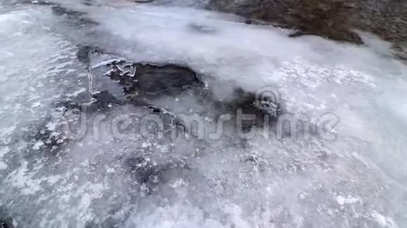 当水从冰冻的雪覆盖的河流下面经过时气泡在冰下移动视频的预览图