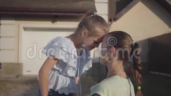 肖像小可爱女孩和妈妈站在后院户外关系妈妈和女儿真正幸福的家庭视频的预览图
