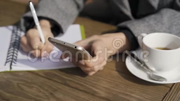 一位年轻的白种人女士在咖啡馆里坐在桌子旁手里拿着手机那个女孩在她身上扭动视频的预览图