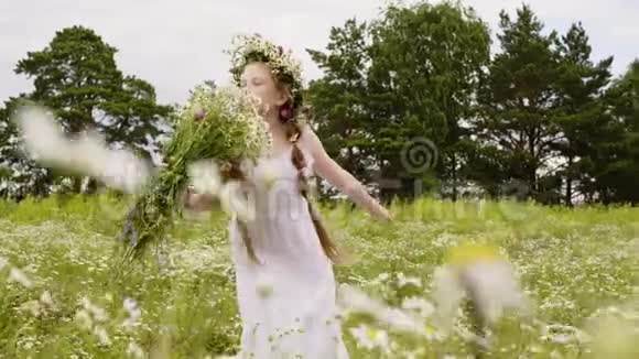 花圈里的少女在盛开的田野上嗅着花束时尚模特摆着夏日鲜花视频的预览图