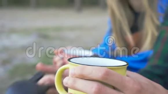 一对夫妇把茶倒进黄色的杯子里长途旅行后游客们在森林里休息视频的预览图