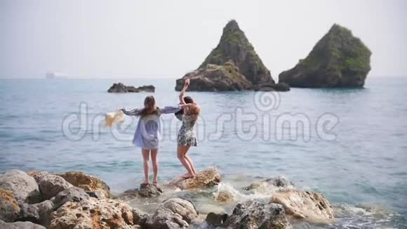 两个漂亮的女人站在大石头上挥舞着手视频的预览图