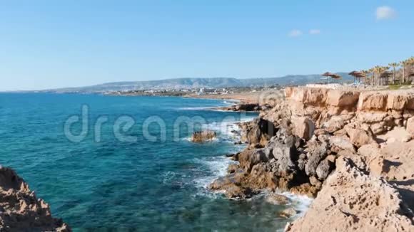 岩石海岸的侧景岩石峭壁清澈湛蓝的海水被海包围的悬崖边缘海浪冲击海岸视频的预览图