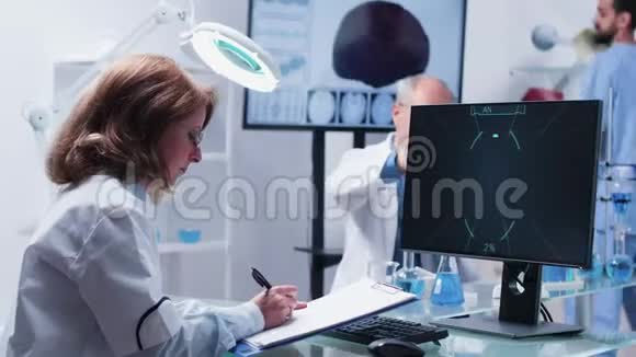 女科学家在电脑显示器的剪贴板上做笔记视频的预览图