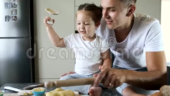 父亲和女儿穿着白色T恤在现代厨房做饭视频的预览图