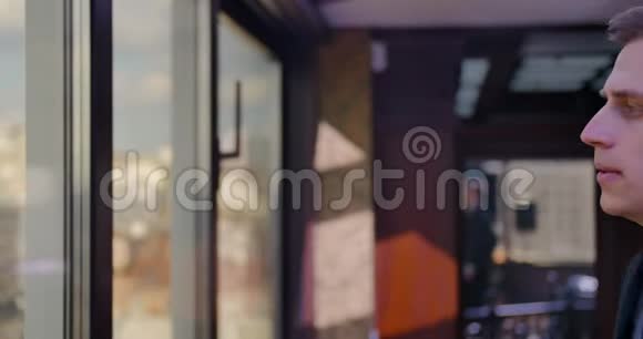 一个穿着燕尾服的金发男人走近窗户沉思欣赏全景做出决定金融商人视频的预览图
