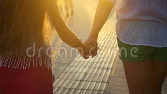 妈妈和女儿在日落时散步牵手太阳阳光透过你的手指照耀爱幸福和幸福视频的预览图