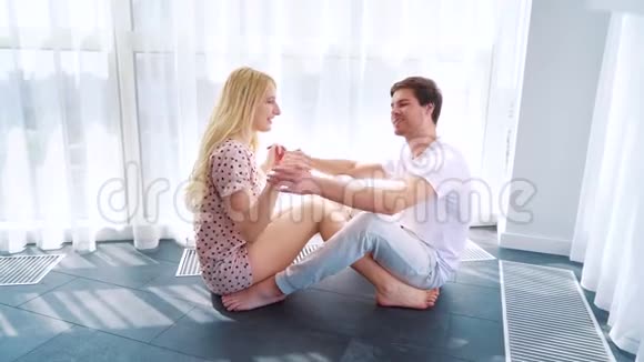 年轻的恋人们坐在地板上手牵手快乐的早晨视频的预览图