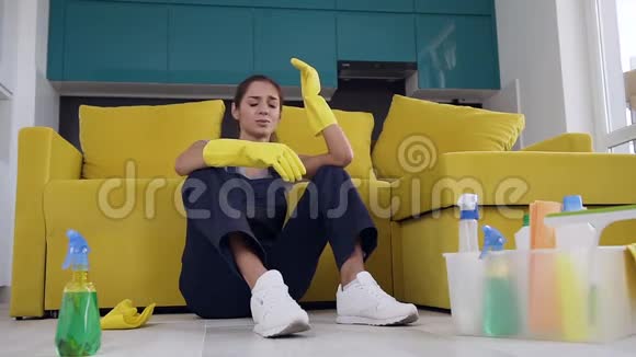疲惫的女清洁工坐在沙发旁洗完木地板后感到疲惫视频的预览图