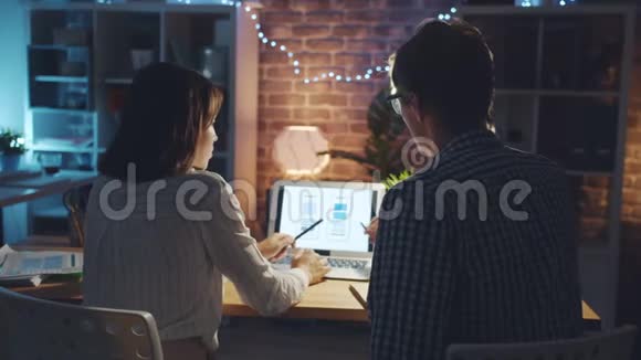 女孩和男人的智能手机界面设计师在办公室工作的笔记本电脑视频的预览图