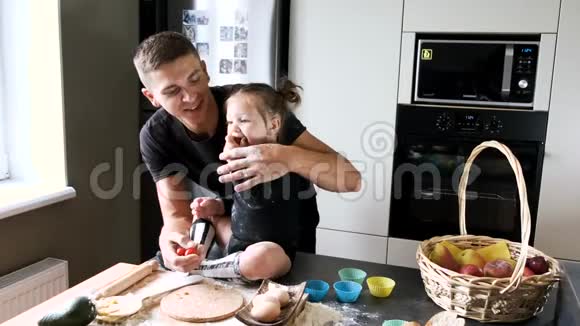 爸爸和小女孩穿着黑色T恤衫在厨房做饭视频的预览图
