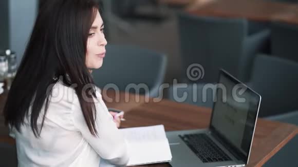 女商人在咖啡馆工作在笔记本上写笔记慢动作视频的预览图