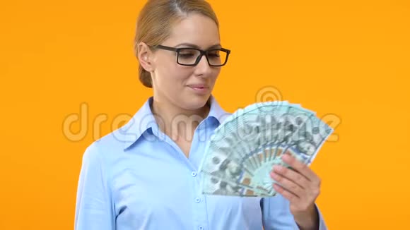 穿西装的漂亮女人指着一堆钱赚钱的生意视频的预览图