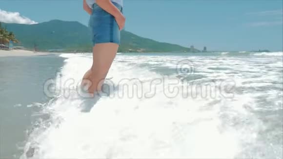 在热带海滩上女人的腿欧洲美丽的布鲁内特沿着海滩散步慢动作视频的预览图