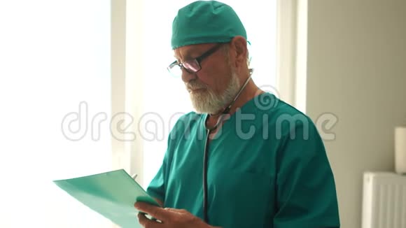 成熟的男医生穿着绿色医疗制服阅读病人病史医生治疗师在一个绕道视频的预览图
