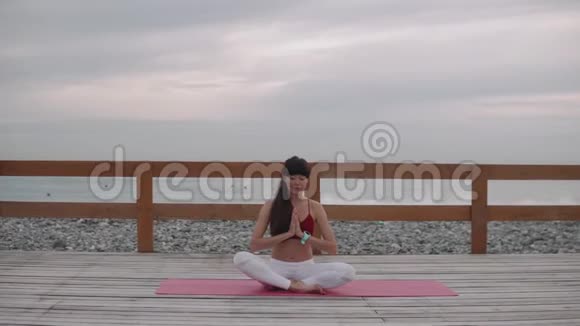 女运动员集中精力呼吸双腿交叉坐在海滨视频的预览图