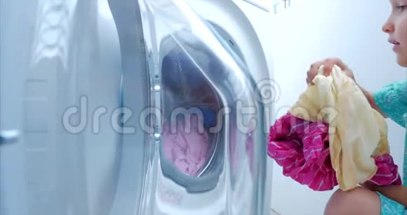 将衣服装入洗衣机小女孩把衣服装在洗衣机里包括洗衣概念视频的预览图