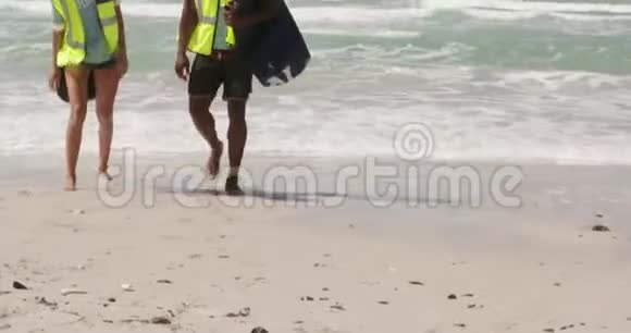 非裔美国人志愿者带着垃圾袋一起在海滩散步的正面景色视频的预览图