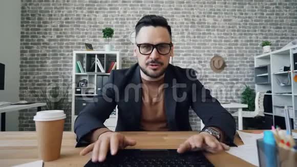胡子男用电脑上网聊天看着办公室里的镜头打手势视频的预览图