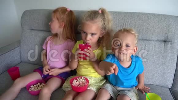 可爱的兄弟姐妹孩子们吃爆米花喝果汁在家电影院看电影视频的预览图