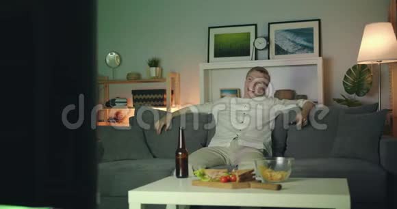 快乐的男人在家看电视在床上笑晚上独自享受喜剧视频的预览图