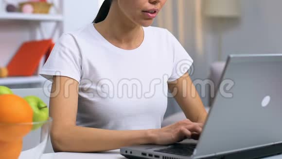 女士自由职业者在笔记本电脑蚂蚁家和吃苹果健康的零食视频的预览图
