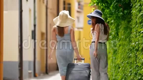 两个女人沿着小巷走到她们的右边一堵绿色的墙视频的预览图