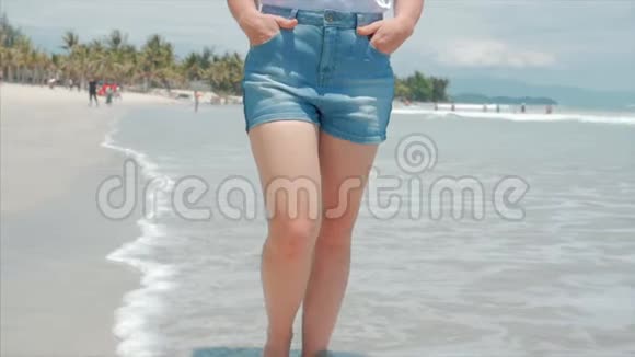 在热带海滩上女人的腿欧洲美丽的布鲁内特沿着海滩散步慢动作视频的预览图