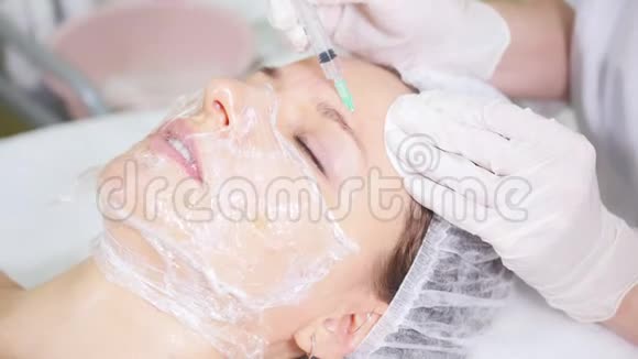 中间疗法美容师做面部美容手术在病人前额注射并交谈视频的预览图