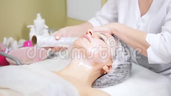 美容师在美容诊所做美容手术在客户的面部包装视频的预览图
