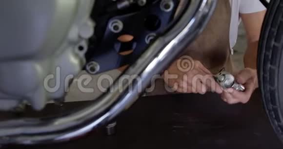 男机修工在4k车库修理摩托车时用手机说话视频的预览图