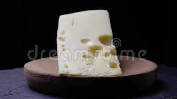 有洞的奶酪在深色背景的木盘上旋转视频的预览图
