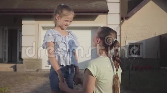肖像小可爱女孩亲吻她的母亲站在后院户外关系妈妈和女儿实际视频的预览图