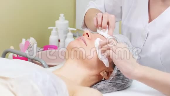 美容师在客户的脸颊上擦奶油做美容手术清洁面部美容视频的预览图